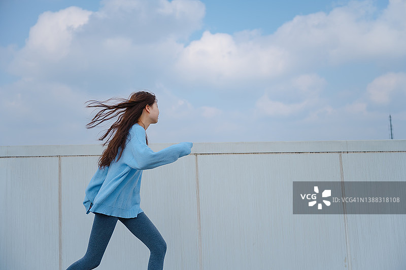 亚洲美丽的女孩快乐地奔跑在一个阳光明媚的日子图片素材