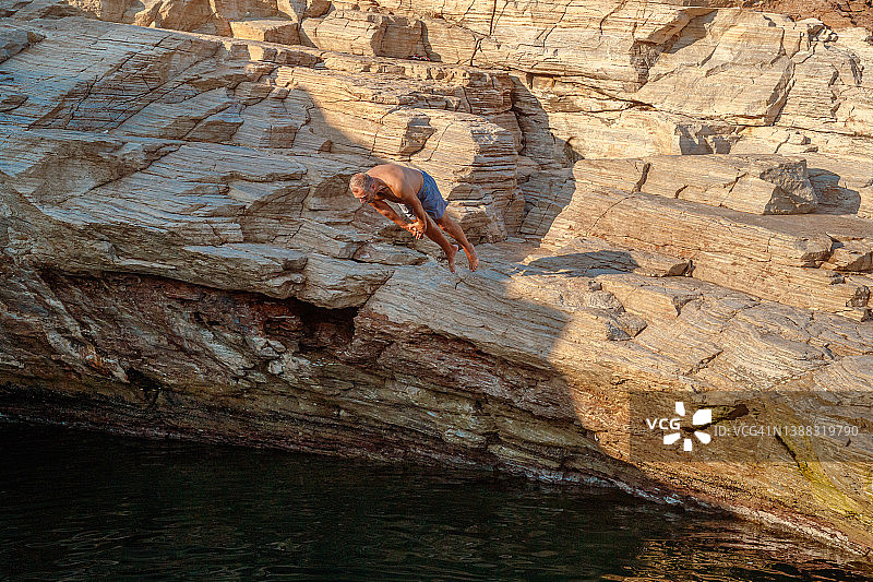 男人穿泳裤头朝上从悬崖跳入海水中图片素材