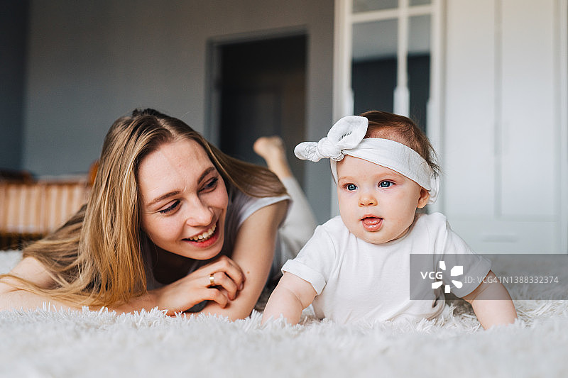 年轻的母亲和女儿共度时光，周末活动，躺在床上图片素材