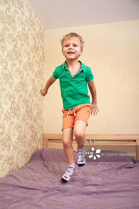 快乐的男孩在床上跳跃图片素材