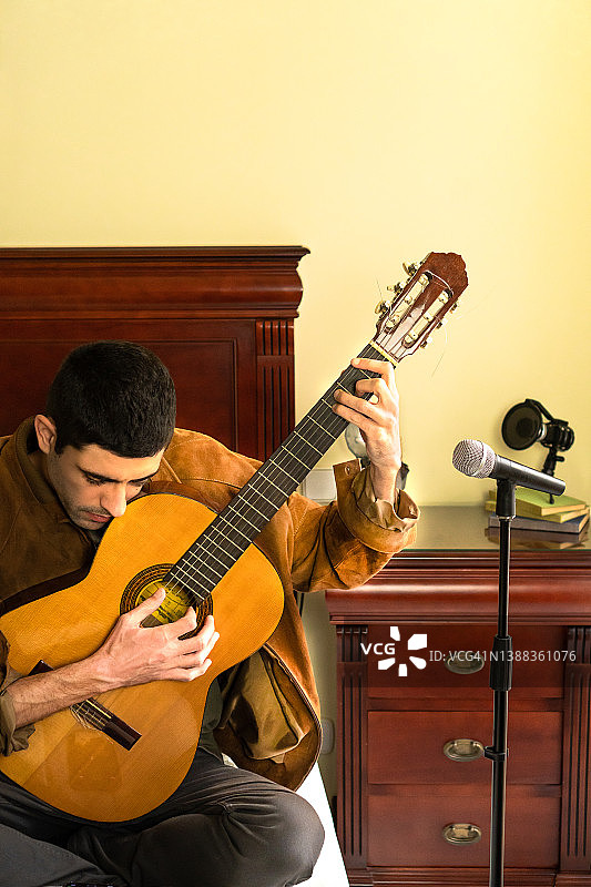 吉他手在床上演奏古典吉他并录制音乐图片素材