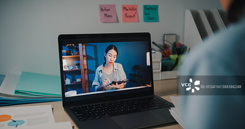 在办公室夜晚坐在办公桌旁通过笔记本电脑进行视频通话的年轻女商人图片素材