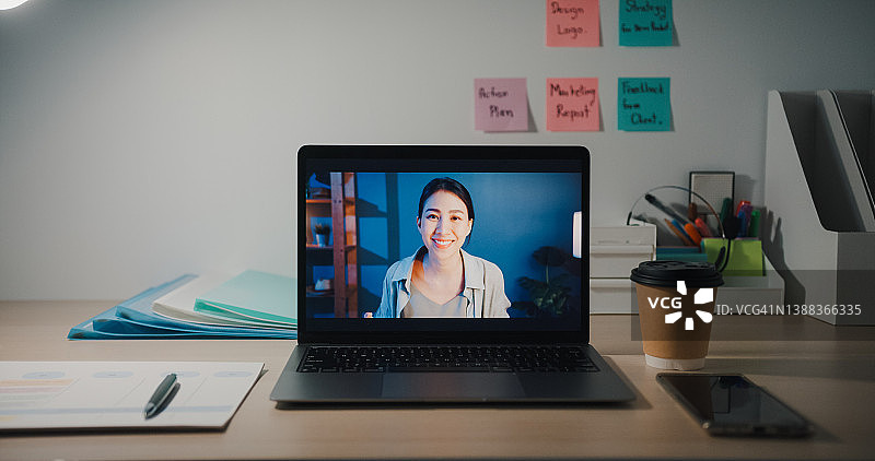 年轻女商人晚上在办公室的办公桌前通过笔记本电脑进行视频通话图片素材