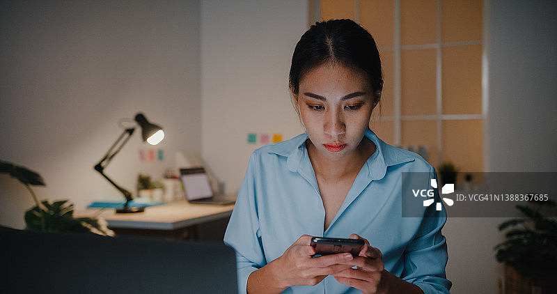 年轻女商人晚上在办公室的办公桌旁打电话图片素材