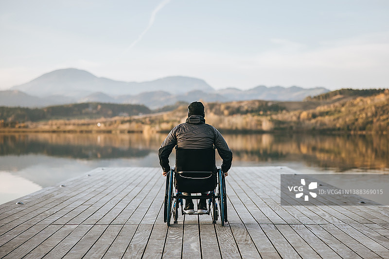 坐在轮椅上在码头欣赏风景的残疾男人图片素材