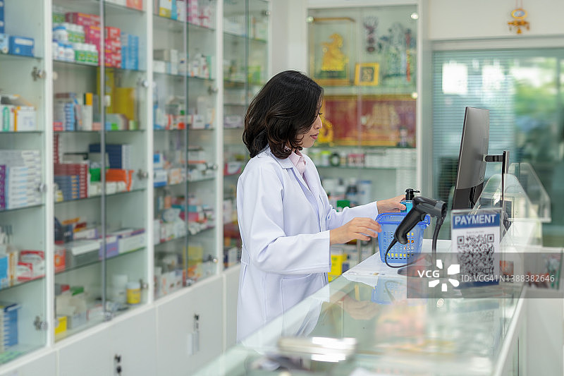 亚洲药剂师在当地药房检查药丸，根据处方进行交易付款。当地小型药房业务。医疗保健概念。图片素材