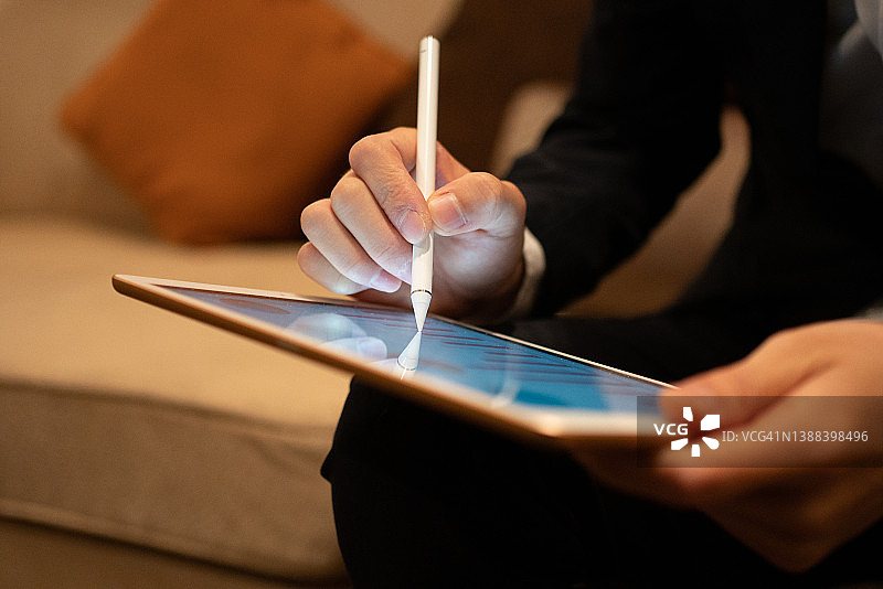 亚洲男人用笔在平板电脑上书写图片素材