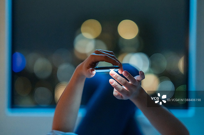 晚上躺在床上用智能手机的女人图片素材