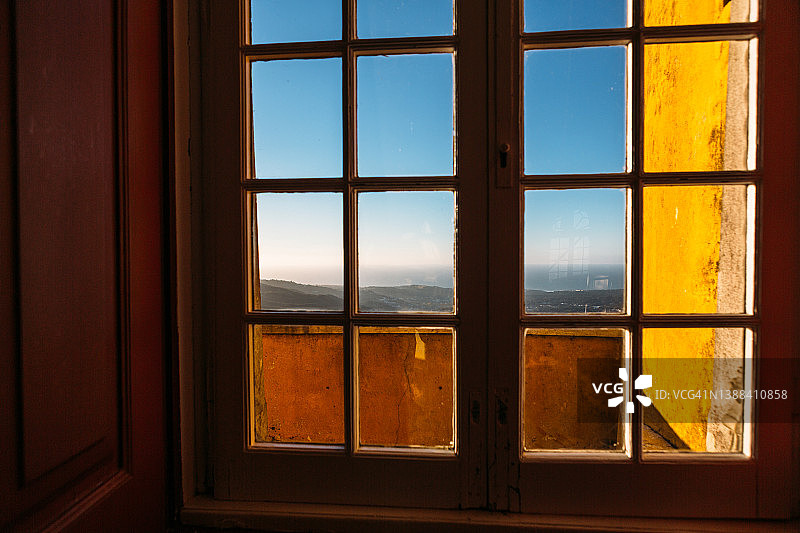 透过旧窗框看到的广阔风景和海岸线暮色图片素材