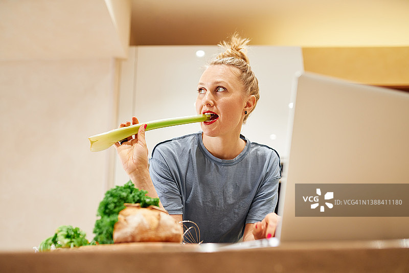 在厨房里吃芹菜的女人图片素材