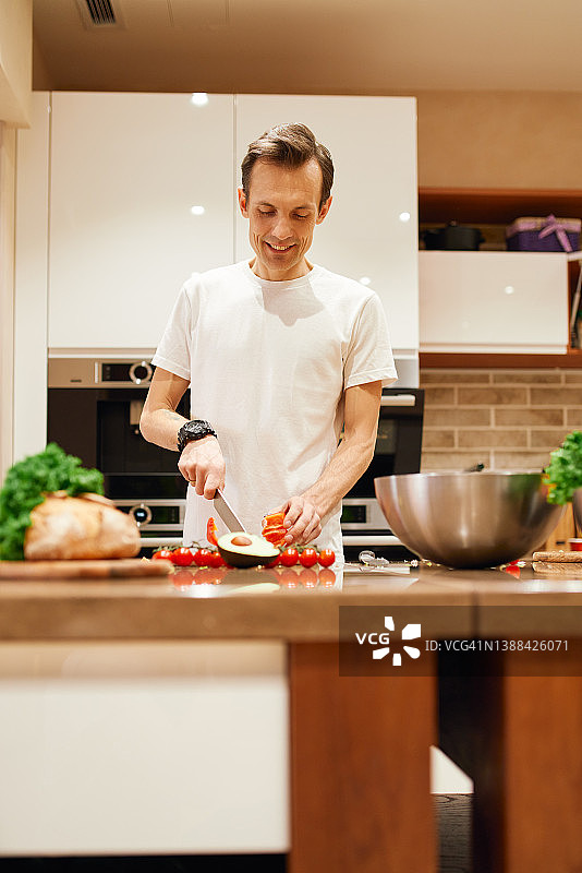 在厨房做沙拉午餐的积极男人图片素材