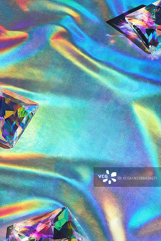 迪斯科霓虹反射彩虹全息纺织背景上的玻璃水晶和珠子图片素材
