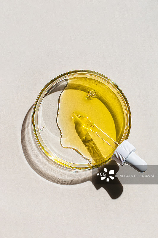 米色背景上的移液器和化妆品液体培养皿：化妆品实验室研究概念图片素材