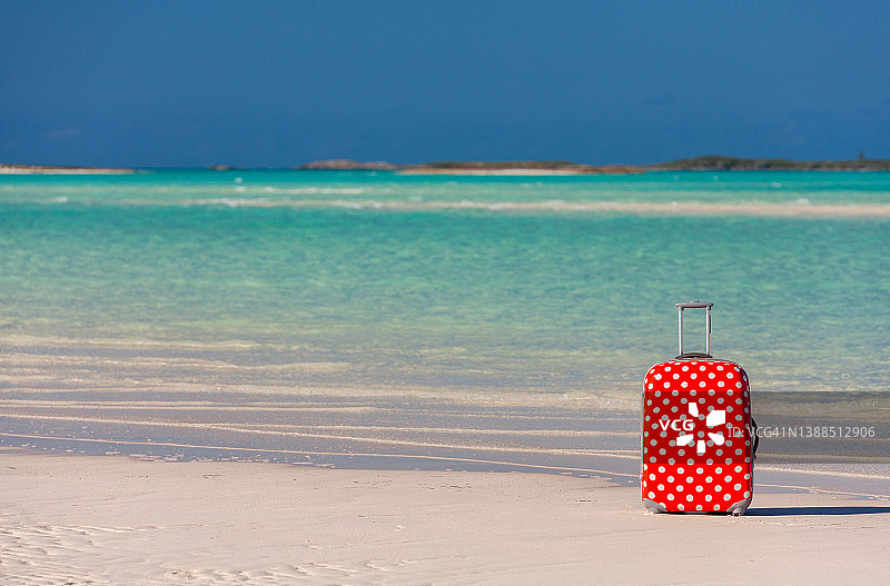 沙滩上的红色波点旅行箱图片素材