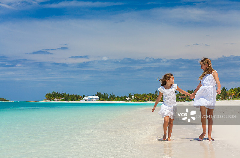 在沙滩上行走的高兴的白人姐妹图片素材