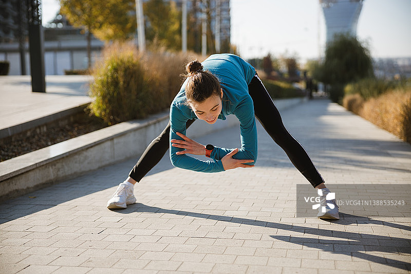 一个年轻女人站在走道上，双腿分开，向前弯腰，双臂交叉图片素材