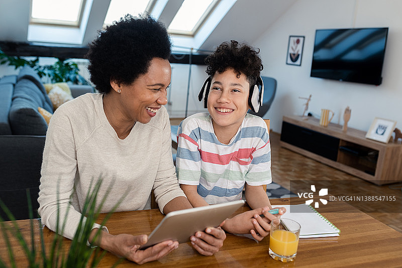 做作业并享受乐趣，同时他的母亲在网上工作的小学生图片素材
