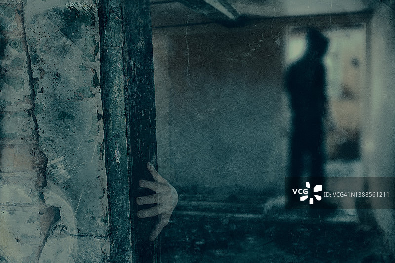 一栋废弃房屋中一个幽灵般的身影的闹鬼概念。带有垃圾摇滚风格的老旧编辑图片素材