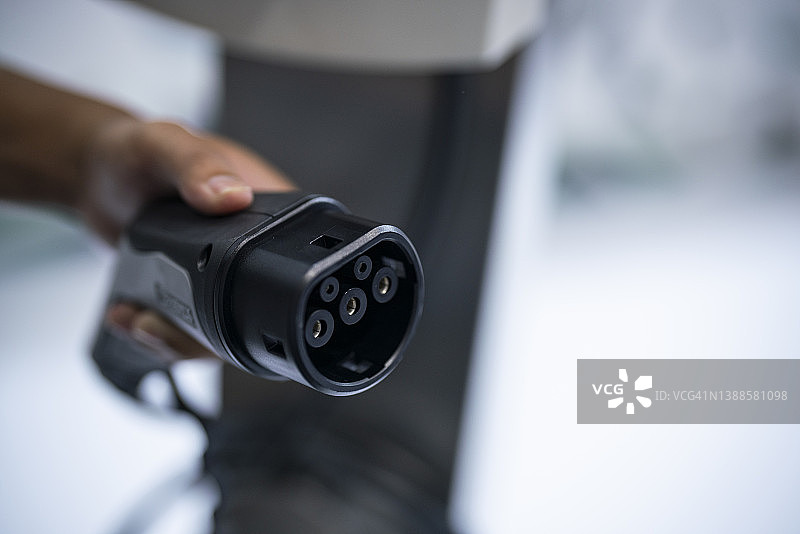 男人手持电动汽车充电线图片素材