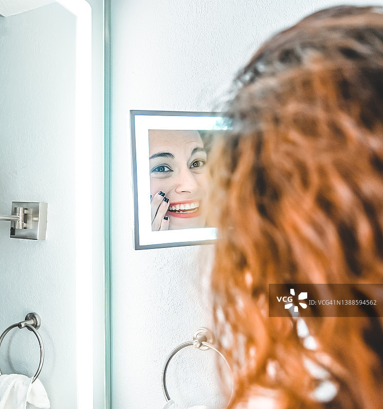 在浴室里对着镜子皱眉的女人图片素材