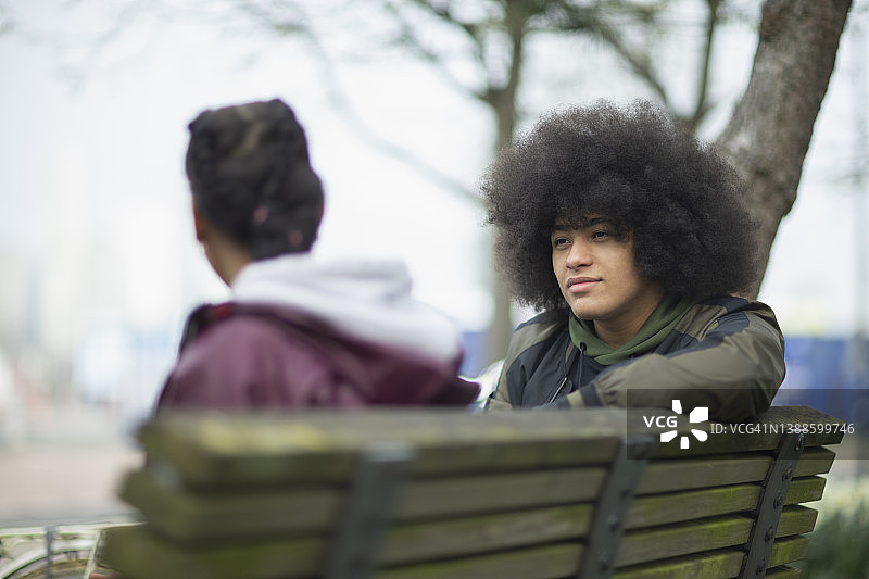 拥有非洲发型的年轻男人在公园长椅上与妹妹交谈图片素材