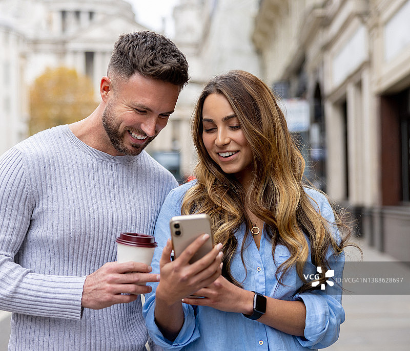 情侣在街上边走边看手机社交媒体图片素材