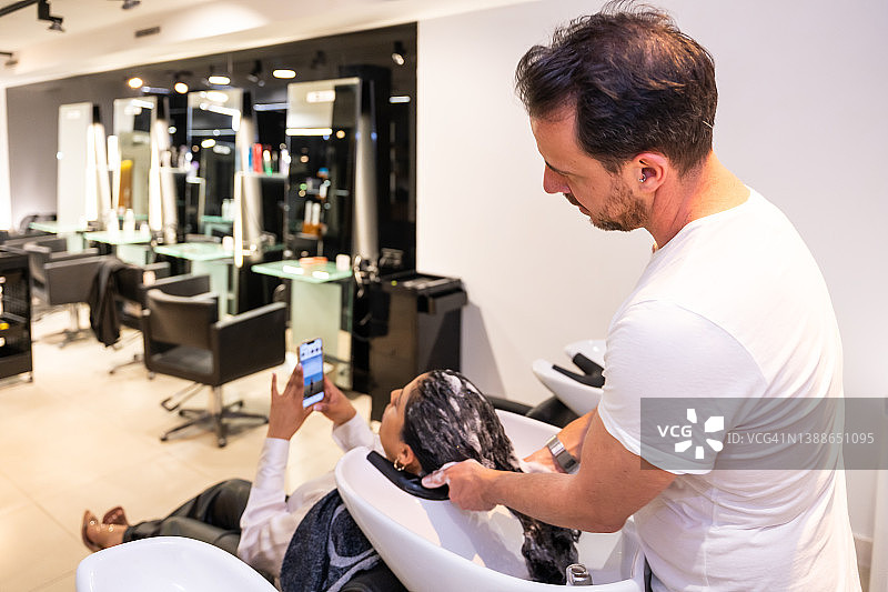 现代豪华美发沙龙，理发师为女顾客清洗卷发图片素材