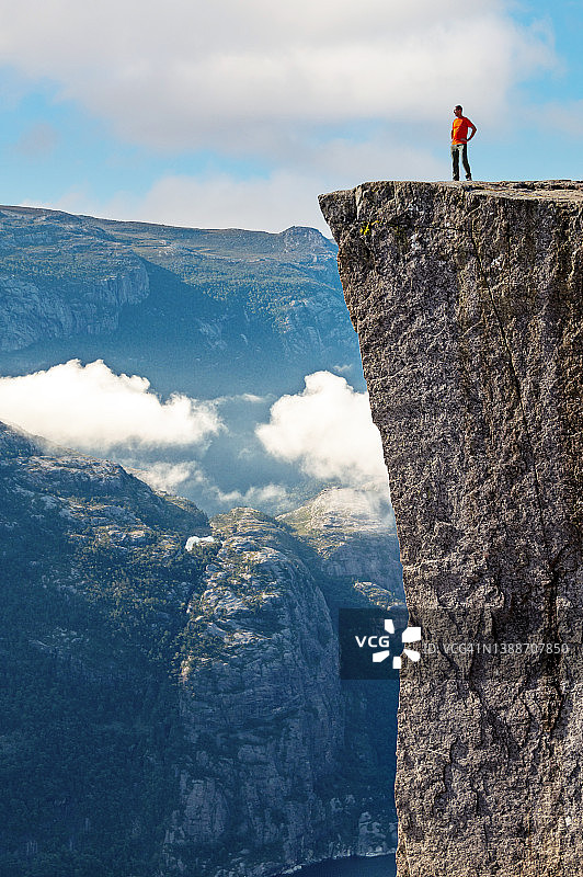 男子坐在布道岩悬崖边，欣赏吕瑟峡湾景色图片素材