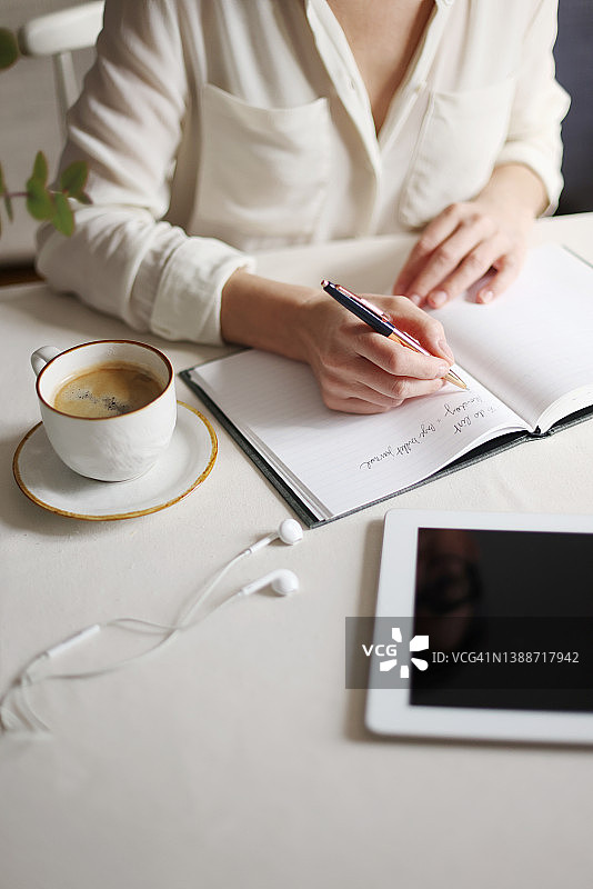 在家工作氛围中，在笔记本上书写的双手特写图片素材