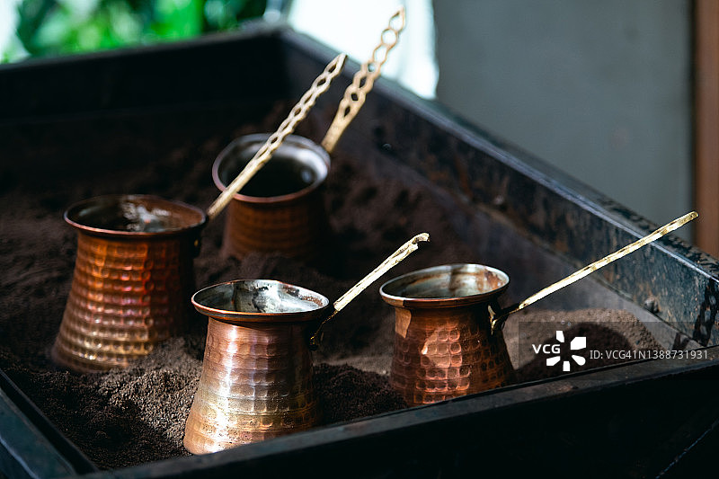 在街头咖啡馆的沙子上用土耳其咖啡壶制作咖啡的过程图片素材