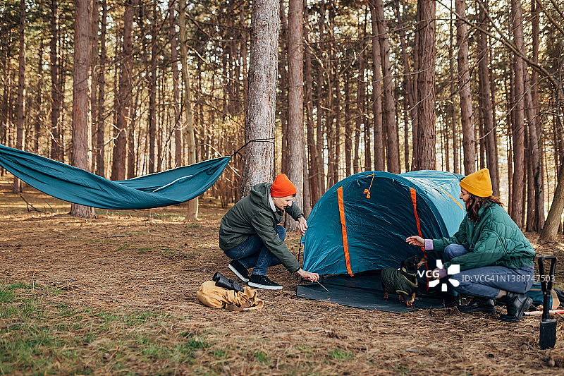 露营旅行中的两位露营者和他们的小黑腊肠犬图片素材