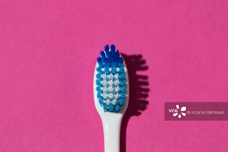 粉色背景上的蓝白毛牙刷细节：口腔卫生、牙齿与牙科概念图片素材