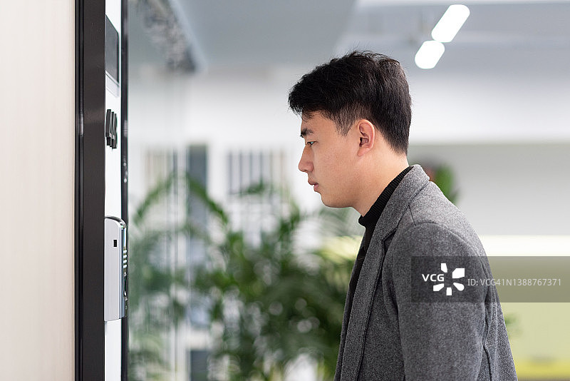 在办公室门口使用面部识别系统的年轻商人图片素材