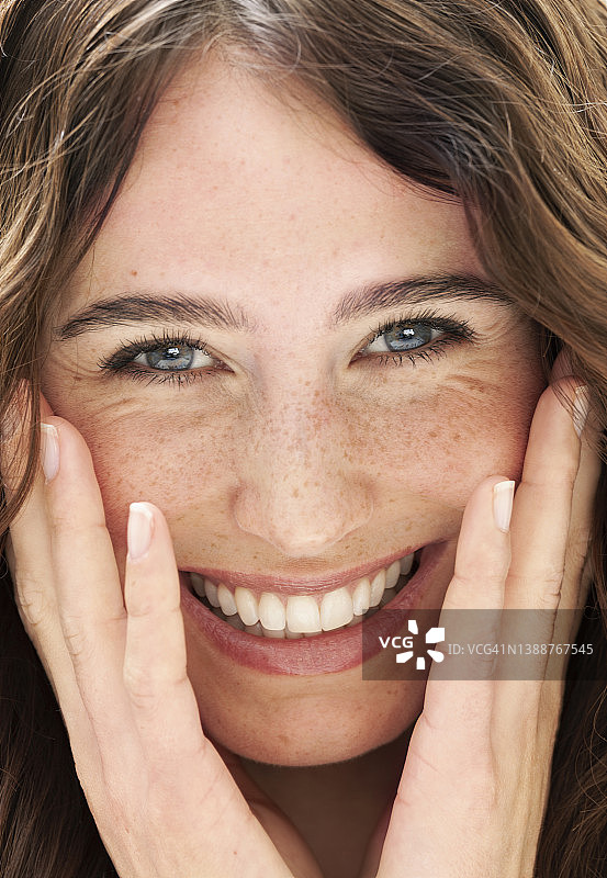 笑容满面的黑发美女特写，双手放在脸颊上图片素材