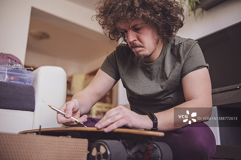 专注的男人正在拆卸电动滑板的螺丝图片素材