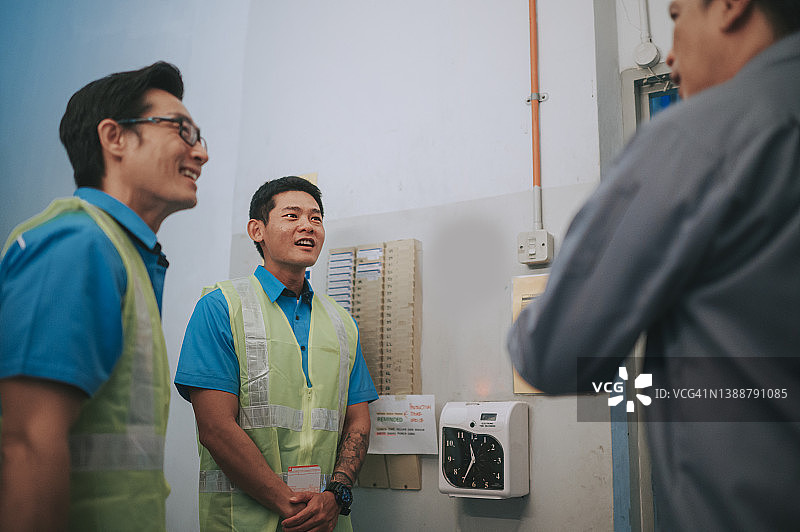 亚洲工人在工厂打卡机旁与主管交谈图片素材