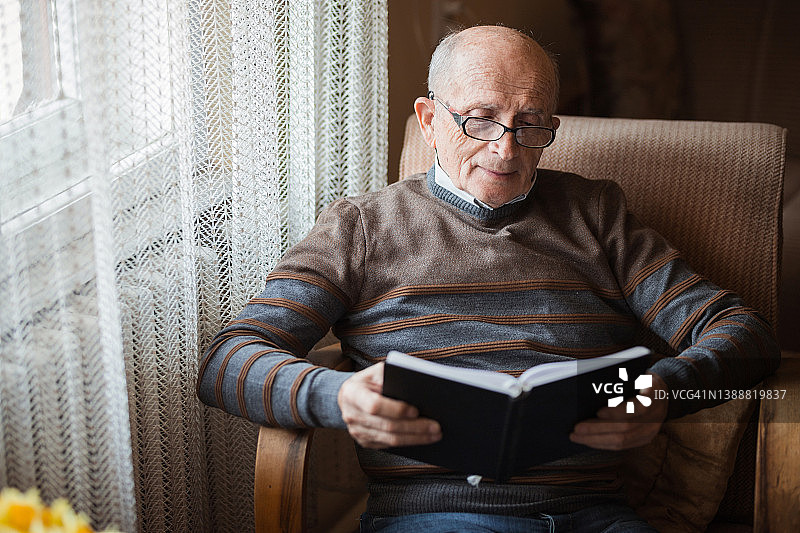 快乐的老人在读书时微笑图片素材