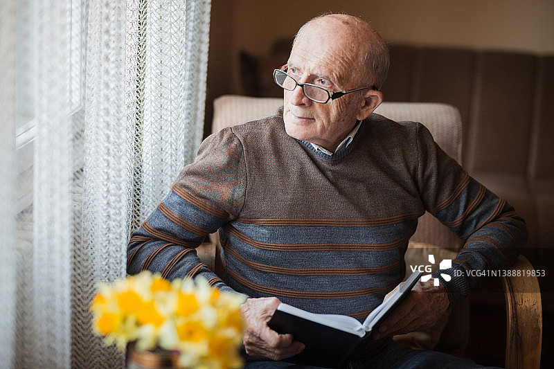 年长的男人在窗边看书图片素材