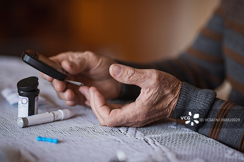 成熟的手做血糖测试的特写图片素材