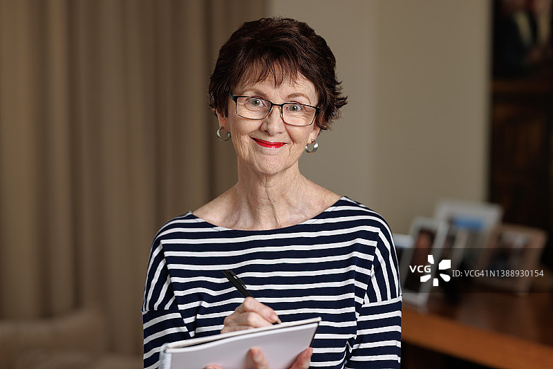 拿着笔和笔记本微笑的女人图片素材