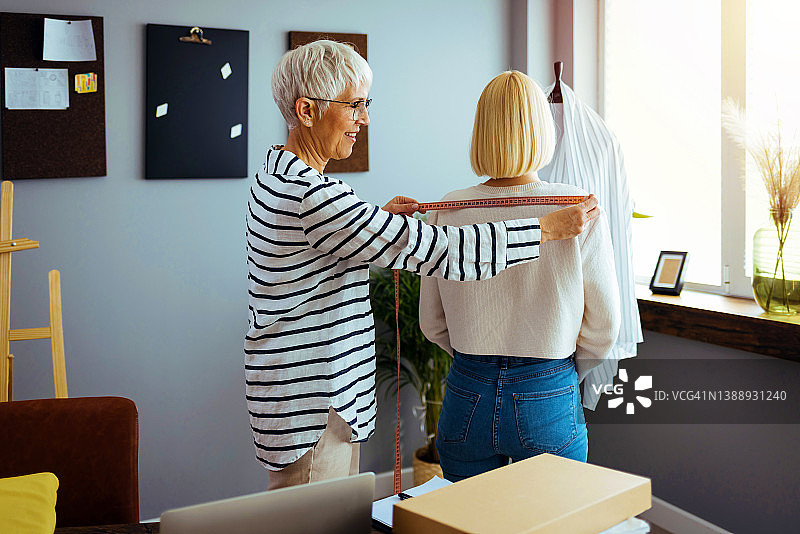 时装设计师在她的时装设计工作室里和模特一起设计服装图片素材