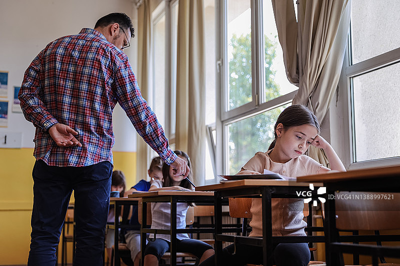 老师在教室里走动，指出学生作业中的错误图片素材