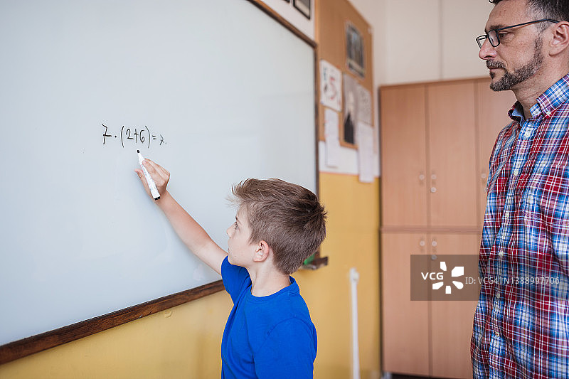 老师观察男生解决数学题图片素材