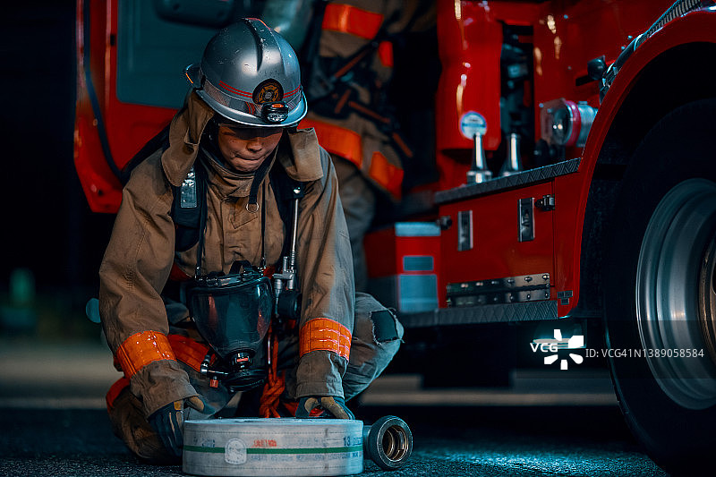 女消防员在消防车旁卷起软管图片素材