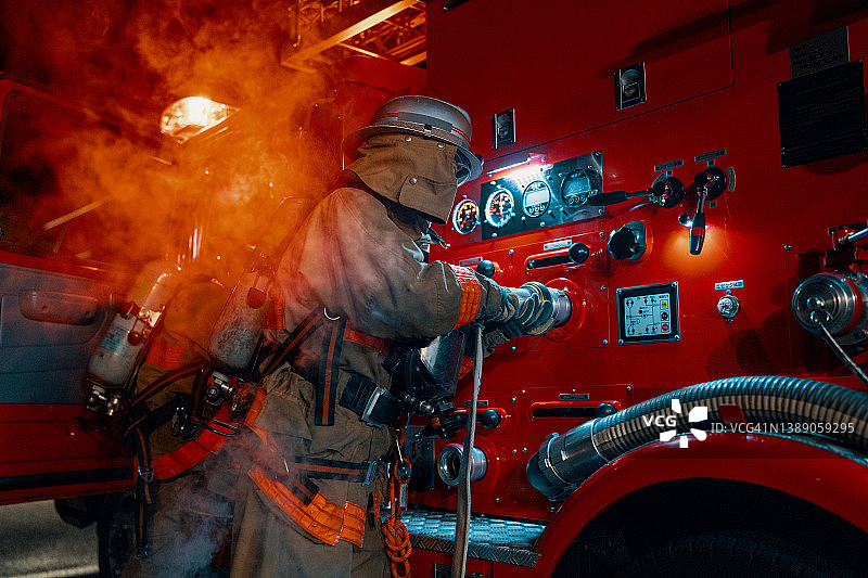 女消防员将软管连接到消防车图片素材
