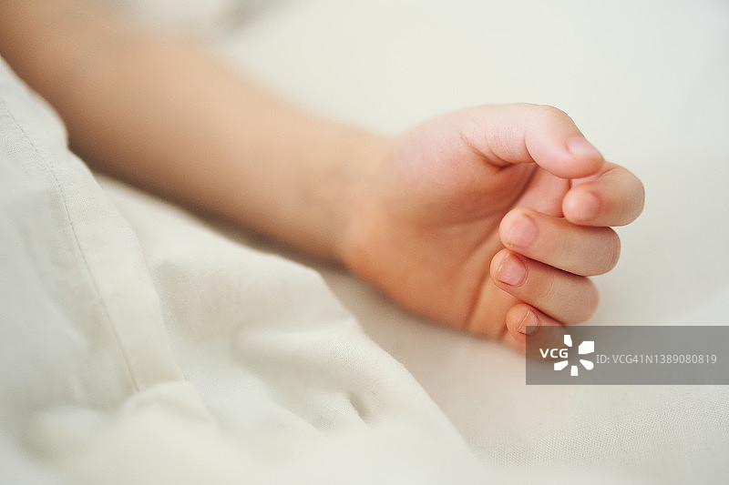 儿童的手放在白色床单上的特写图片素材