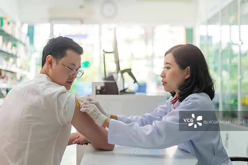 疫苗接种：医生为患者接种疫苗，患者感到高兴和放松。地方药房的健康和医疗概念图片素材