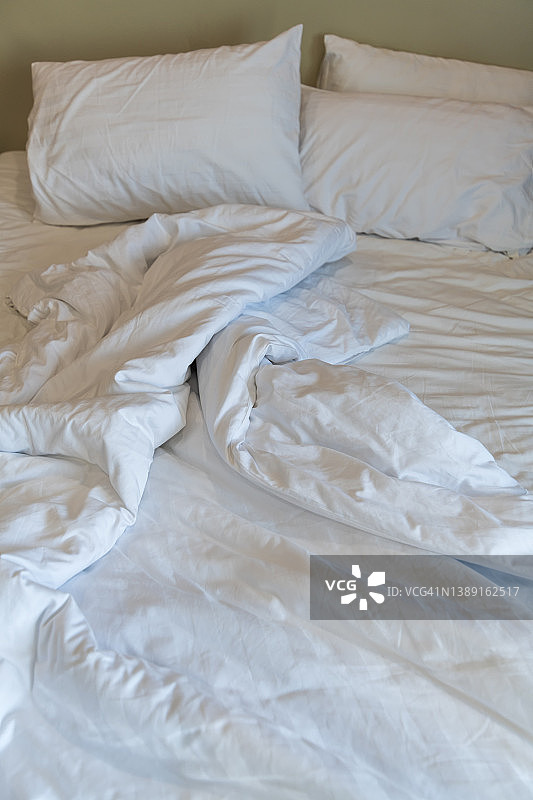 公寓酒店卧室里杂乱的床铺，有被子和枕头图片素材