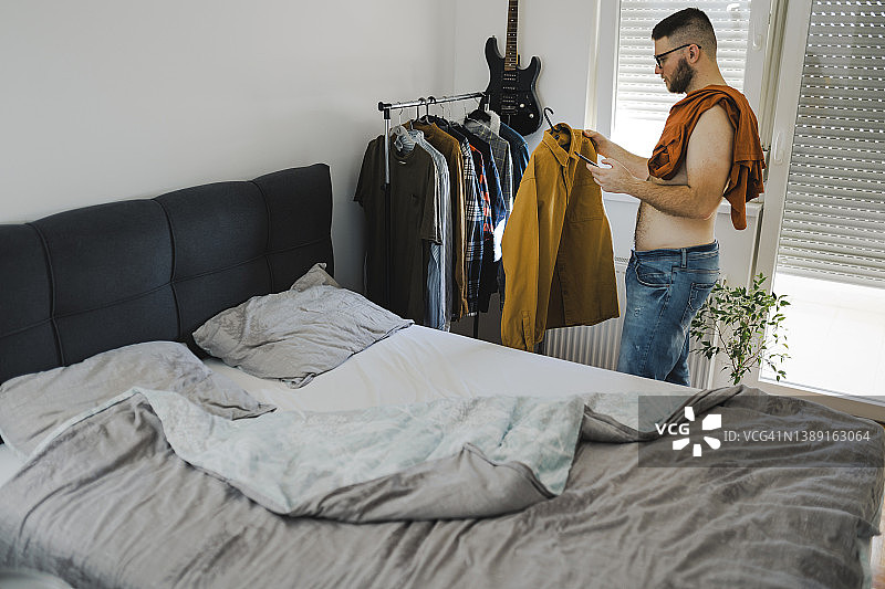 站在衣架前为今天选择服装的年轻人图片素材