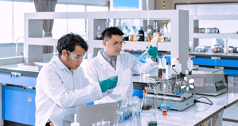亚洲男科学家在实验室工作。医生和科学家在实验室研究新冠病毒图片素材